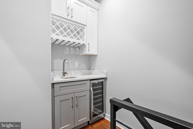 bar with sink, gray cabinetry, white cabinets, beverage cooler, and light hardwood / wood-style flooring