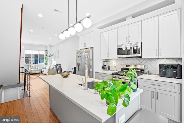 kitchen with white cabinetry, crown molding, decorative light fixtures, stainless steel appliances, and light stone countertops