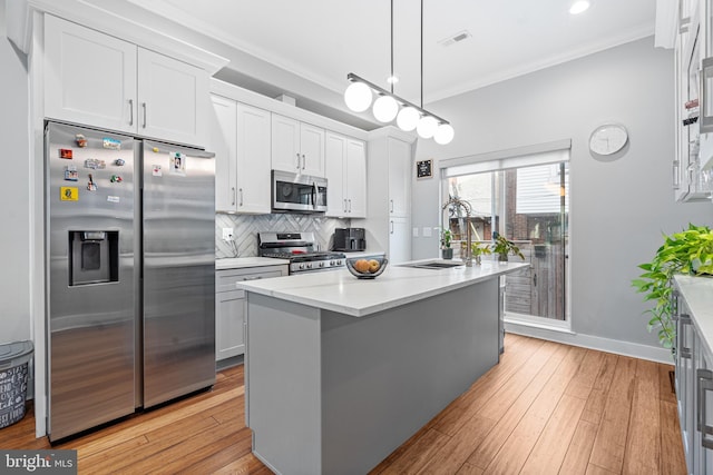 kitchen with pendant lighting, sink, white cabinets, a kitchen island with sink, and stainless steel appliances