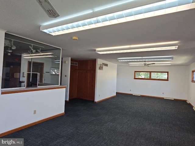 unfurnished room featuring ceiling fan, dark carpet, and baseboards