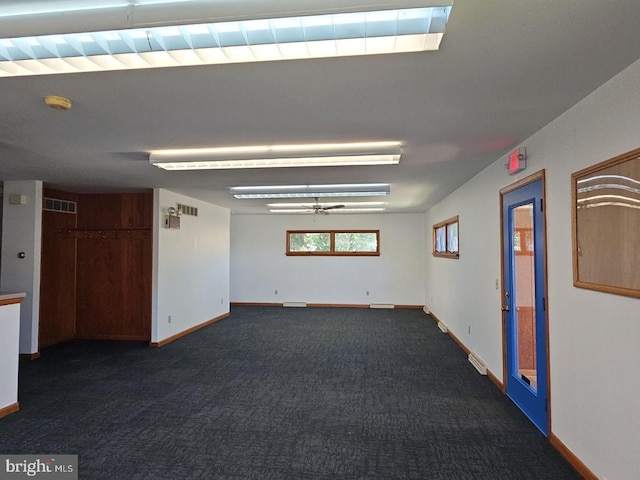 unfurnished room with a ceiling fan, dark carpet, visible vents, and baseboards