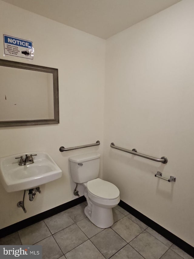 bathroom featuring baseboards, a sink, toilet, and tile patterned floors