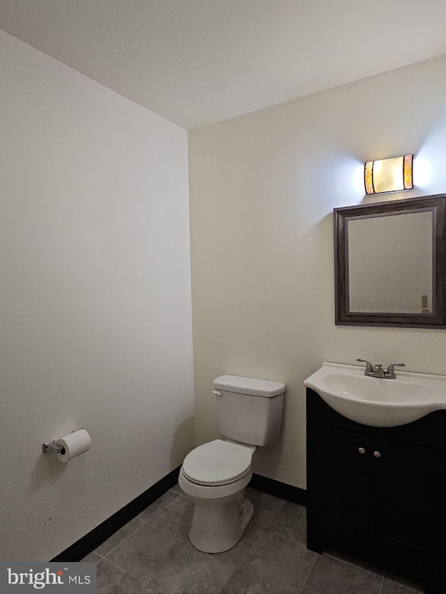 bathroom with toilet, tile patterned floors, baseboards, and vanity