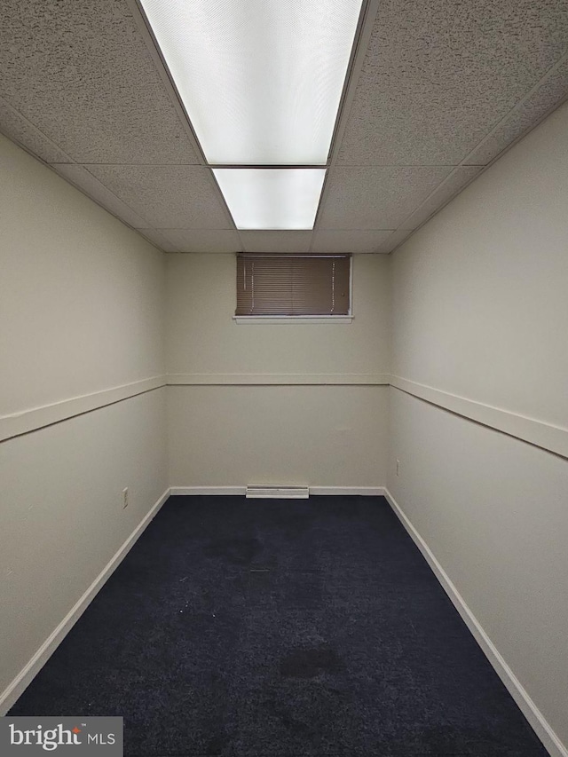 finished below grade area featuring carpet floors, a drop ceiling, and baseboards