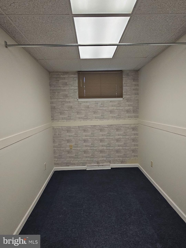 finished basement with a paneled ceiling, carpet floors, and baseboards