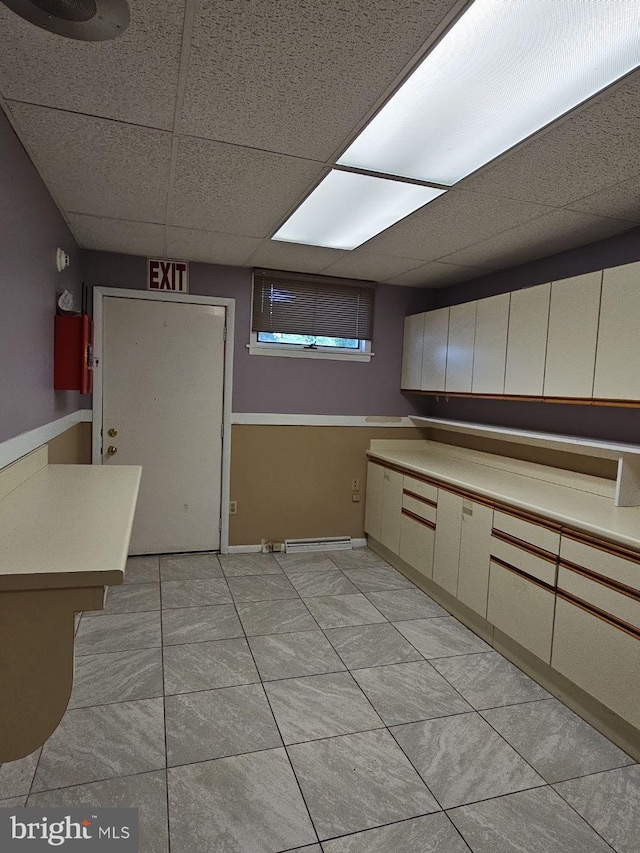 kitchen featuring light tile patterned floors, cream cabinetry, light countertops, and a drop ceiling