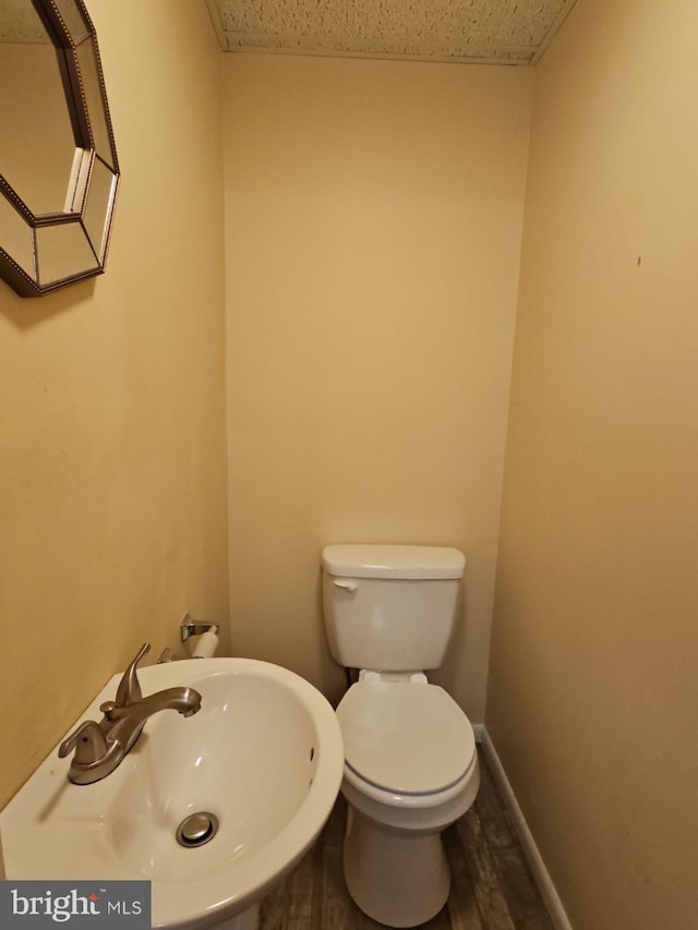 bathroom with wood finished floors, a sink, toilet, and baseboards