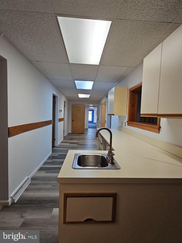 kitchen featuring a paneled ceiling, a peninsula, light countertops, and a sink