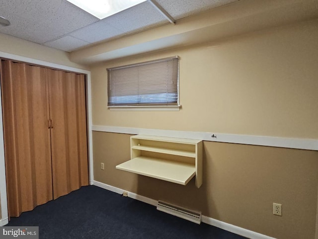 unfurnished bedroom with a drop ceiling, dark carpet, and a closet