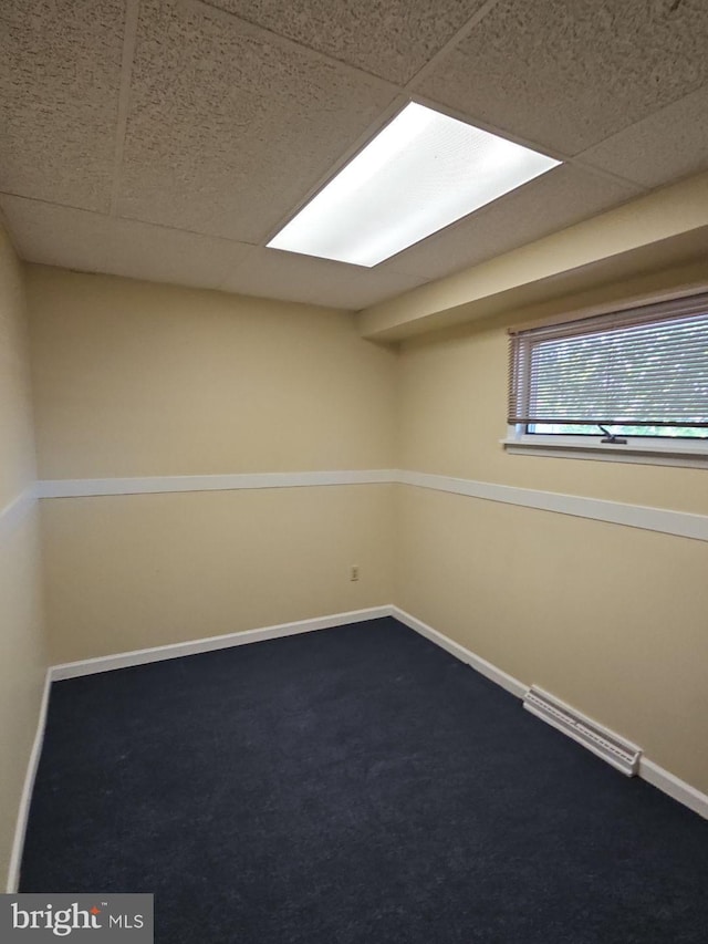 carpeted spare room with a drop ceiling, visible vents, and baseboards