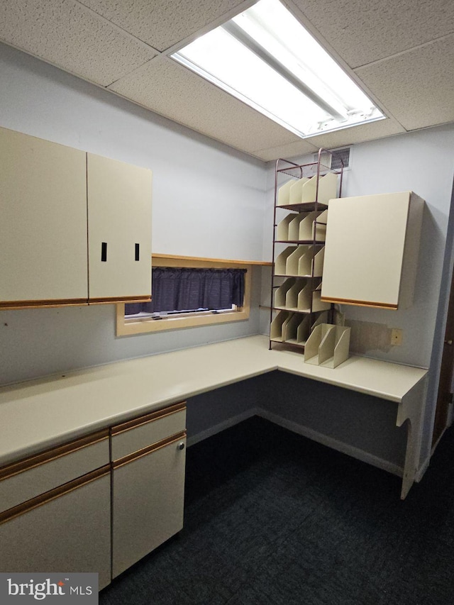 interior space featuring a paneled ceiling and carpet floors