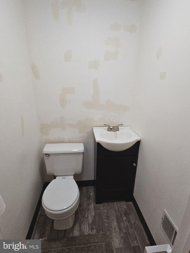 bathroom with visible vents, toilet, vanity, wood finished floors, and baseboards