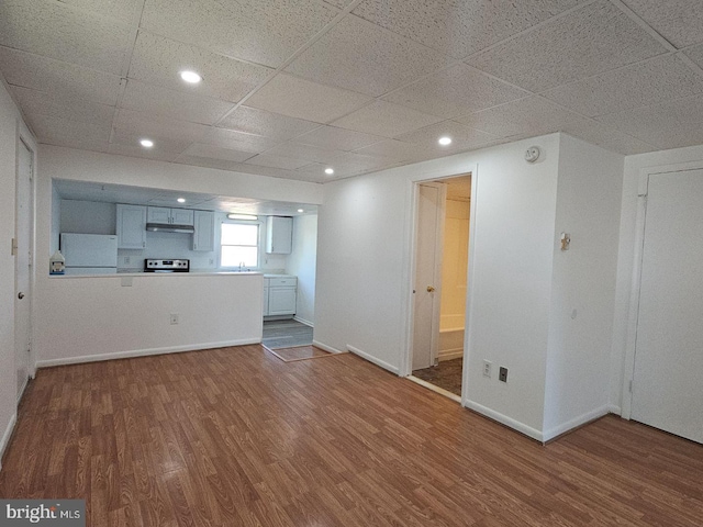 interior space featuring recessed lighting, a drop ceiling, baseboards, and wood finished floors