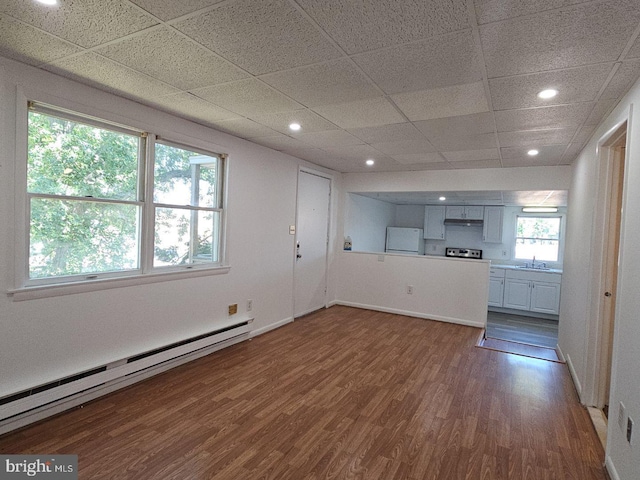 unfurnished living room with a paneled ceiling, sink, hardwood / wood-style floors, and baseboard heating