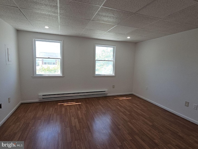 unfurnished room featuring a wealth of natural light, a baseboard radiator, dark hardwood / wood-style floors, and a paneled ceiling