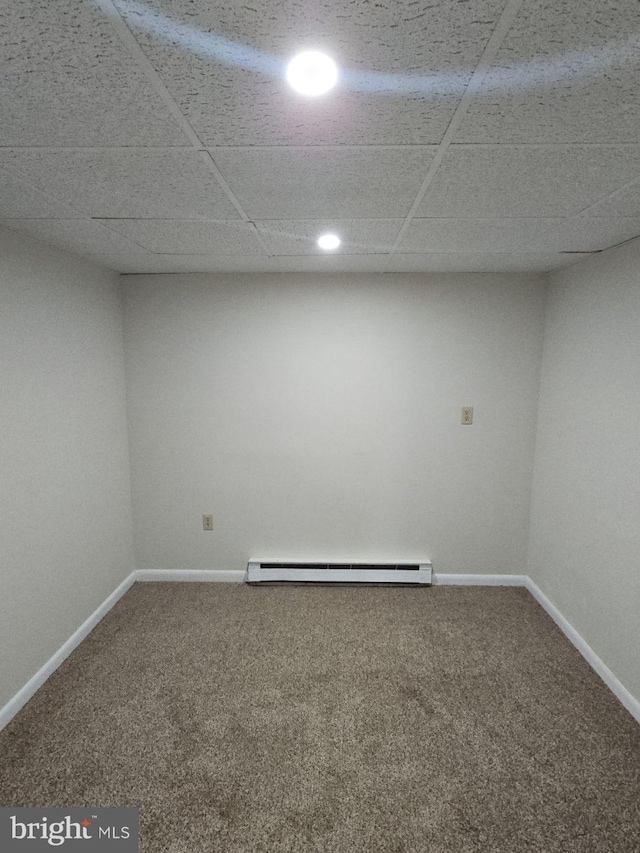 finished basement featuring a baseboard radiator, carpet flooring, a paneled ceiling, and baseboards