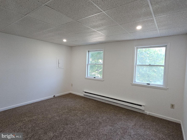 carpeted spare room featuring baseboard heating, a drop ceiling, and a wealth of natural light