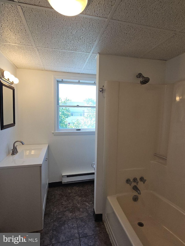 bathroom with a paneled ceiling, vanity, baseboards, baseboard heating, and tub / shower combination