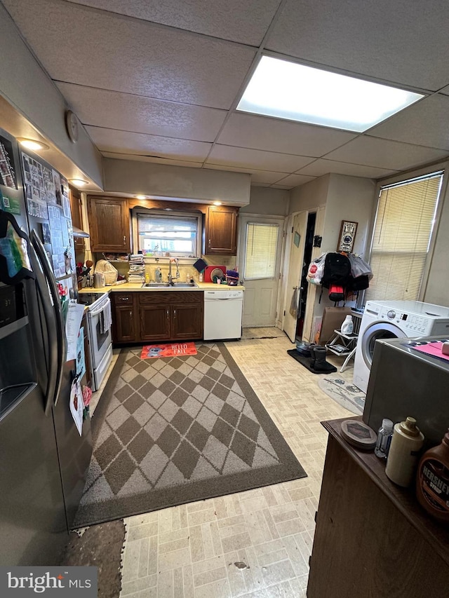 kitchen with white appliances, washer / clothes dryer, sink, and a drop ceiling