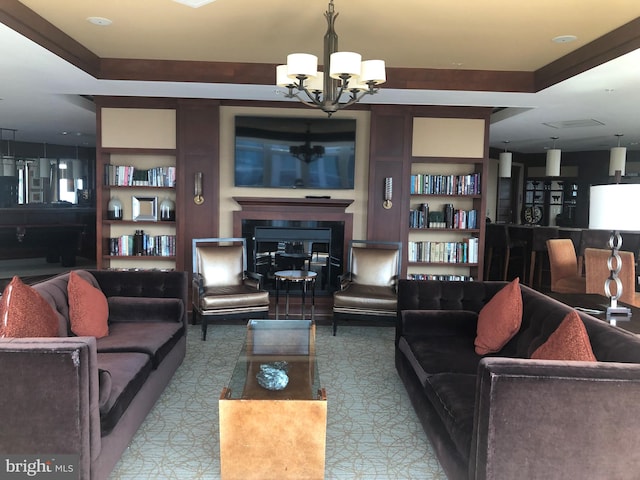 living area with a chandelier, a glass covered fireplace, and built in features