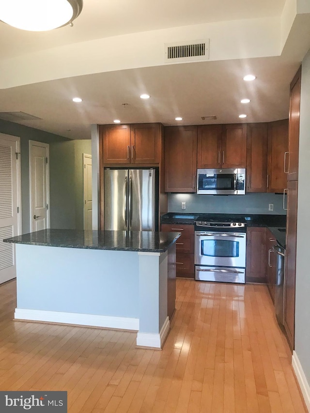 kitchen with stainless steel appliances, a center island, visible vents, and light wood-style floors