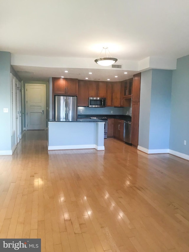 kitchen with stainless steel appliances, dark countertops, visible vents, light wood-type flooring, and baseboards