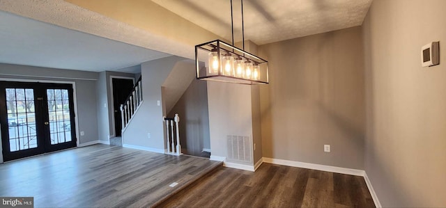 unfurnished dining area with french doors, dark hardwood / wood-style flooring, and an inviting chandelier