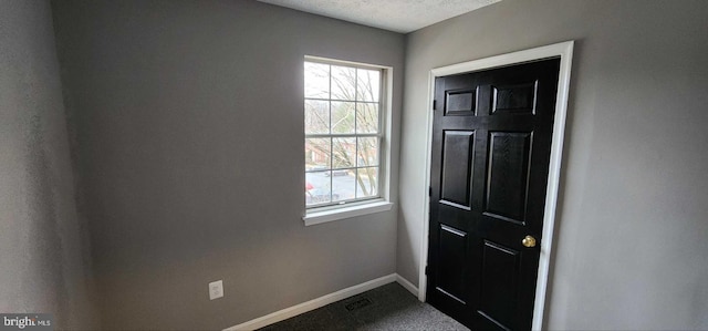 doorway to outside with carpet floors and a textured ceiling