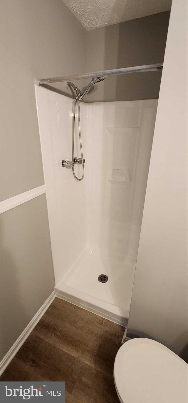 bathroom with walk in shower, hardwood / wood-style floors, a textured ceiling, and toilet