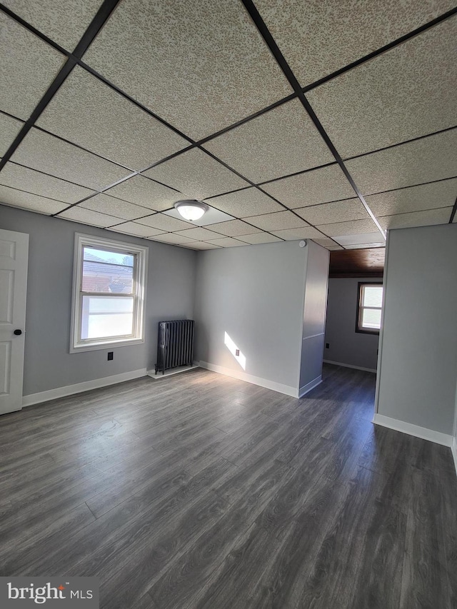 unfurnished living room with dark wood-type flooring and a drop ceiling