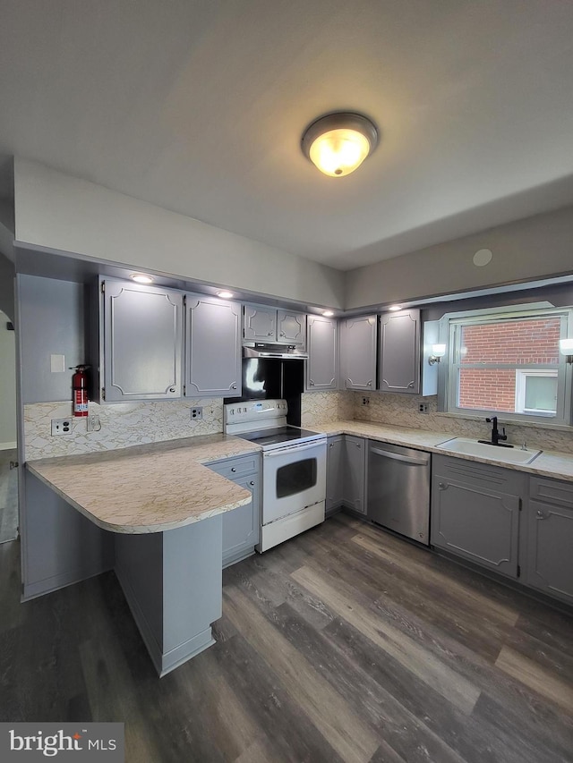 kitchen featuring sink, white range with electric cooktop, dark hardwood / wood-style floors, stainless steel dishwasher, and kitchen peninsula