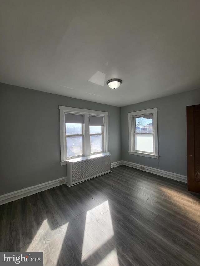 empty room with radiator heating unit and dark hardwood / wood-style floors