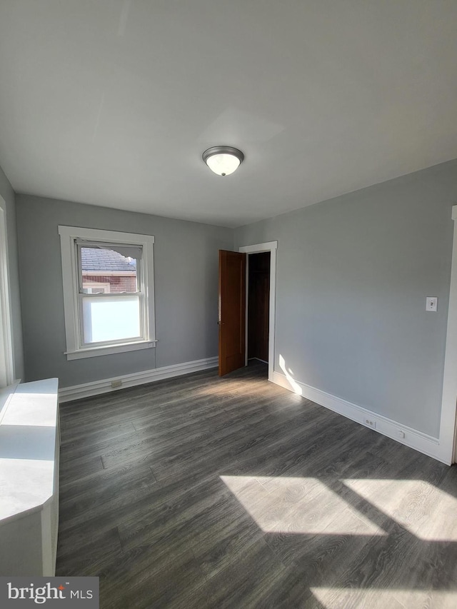 unfurnished room with dark hardwood / wood-style flooring