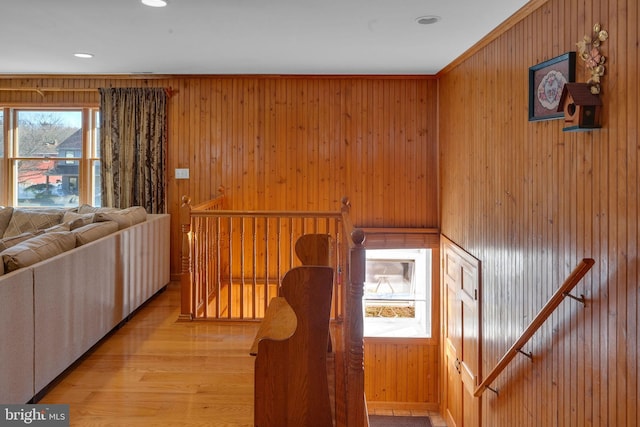 hall with wooden walls and light hardwood / wood-style flooring