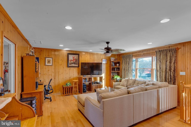 living room featuring ceiling fan, ornamental molding, light hardwood / wood-style flooring, and wood walls