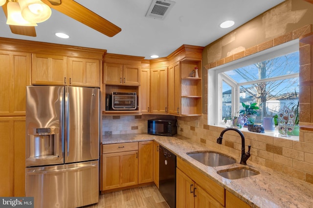 kitchen with sink, light stone counters, tasteful backsplash, light hardwood / wood-style floors, and black appliances