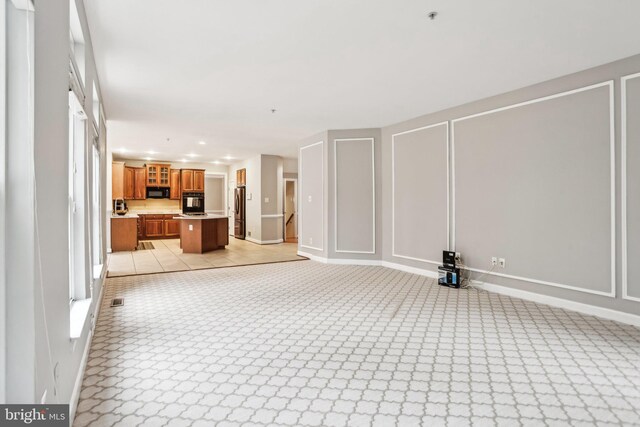 unfurnished living room with light carpet, baseboards, a decorative wall, and recessed lighting