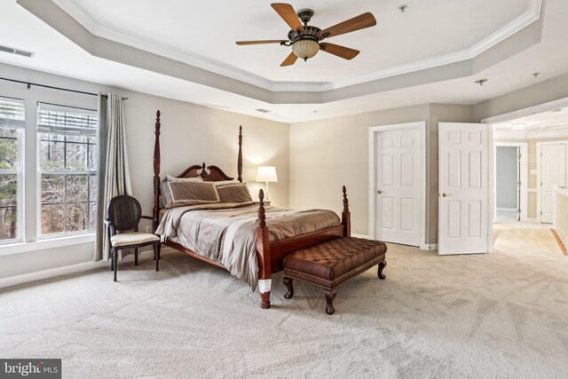 bedroom featuring a tray ceiling, light colored carpet, and crown molding