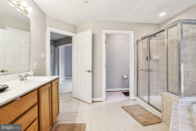 bathroom featuring a stall shower, tile patterned flooring, vanity, and baseboards