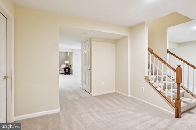 interior space with light carpet, baseboards, and stairs