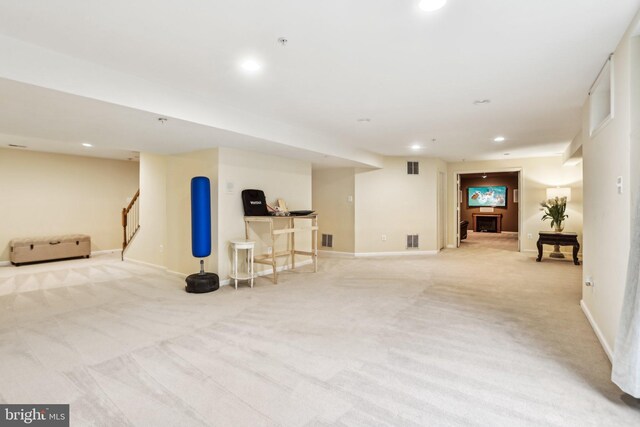 finished basement with light carpet, visible vents, stairway, and recessed lighting