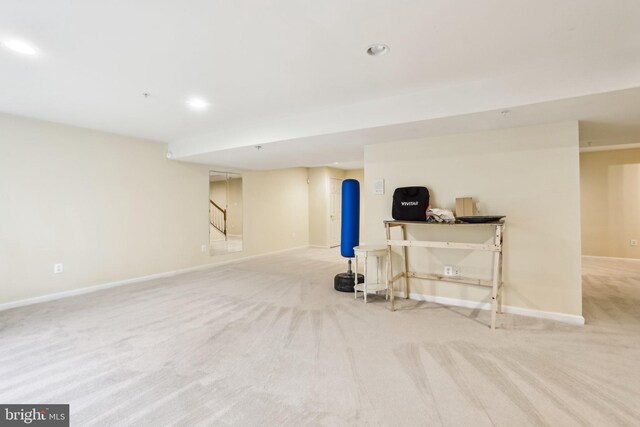 finished below grade area featuring light carpet, stairs, baseboards, and recessed lighting