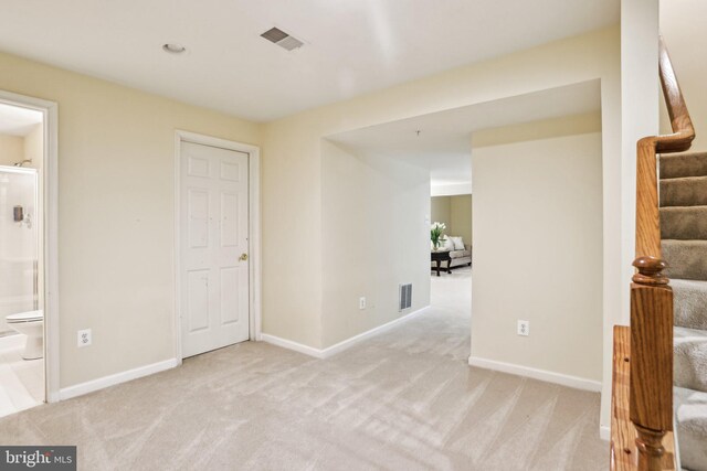 interior space featuring stairs, light carpet, visible vents, and baseboards