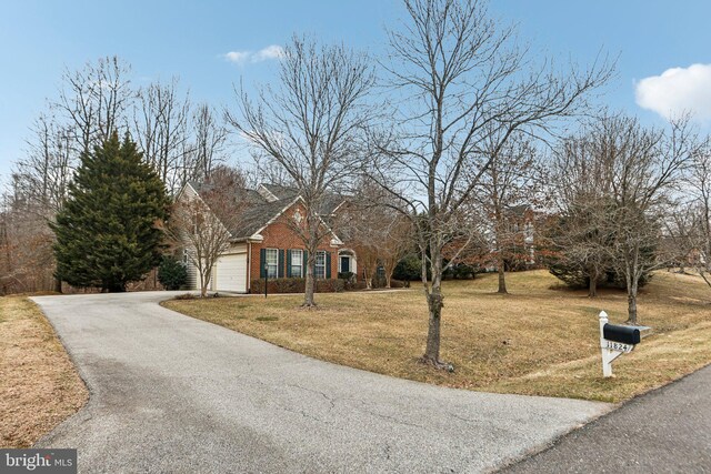 view of front facade with aphalt driveway, a front yard, brick siding, and a garage