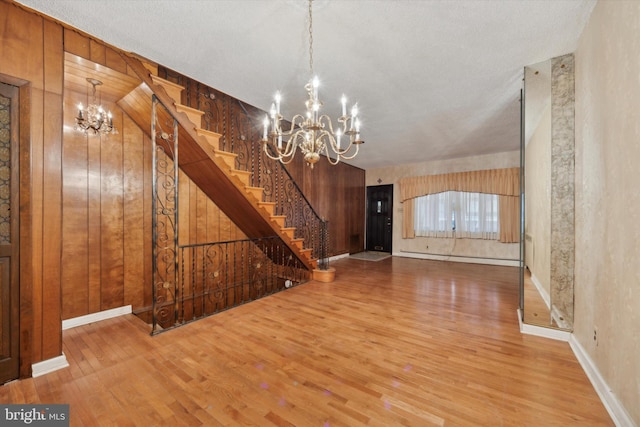 interior space with hardwood / wood-style flooring, wooden walls, a chandelier, and baseboard heating