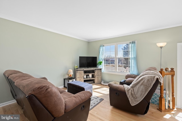 living area with ornamental molding, light wood-style flooring, and baseboards