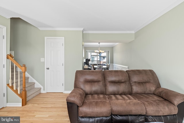 living area featuring a notable chandelier, crown molding, light wood-style flooring, stairway, and baseboards