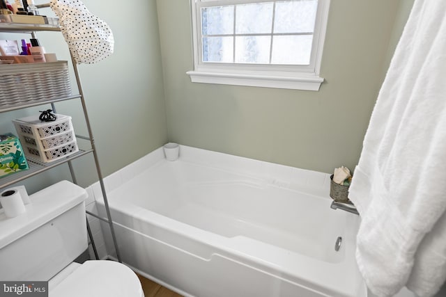 bathroom featuring a garden tub and toilet