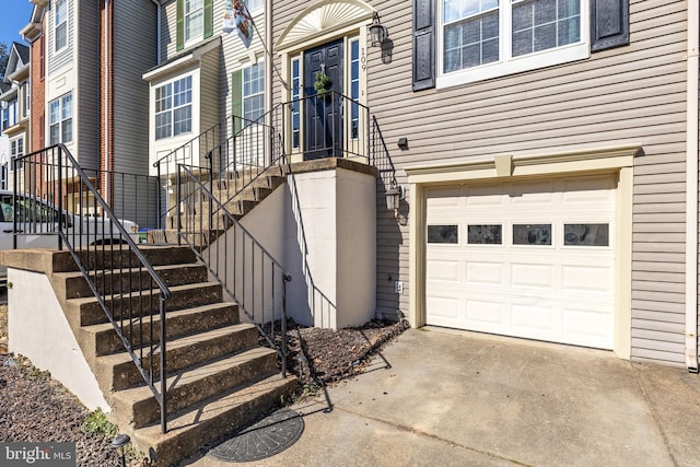 property entrance featuring an attached garage, driveway, and a residential view