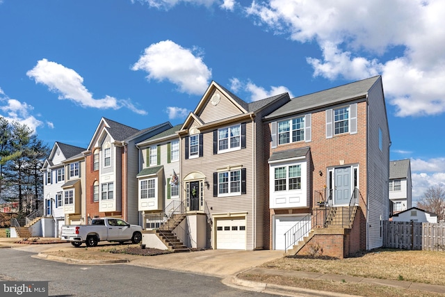 multi unit property featuring driveway, a garage, a residential view, and fence